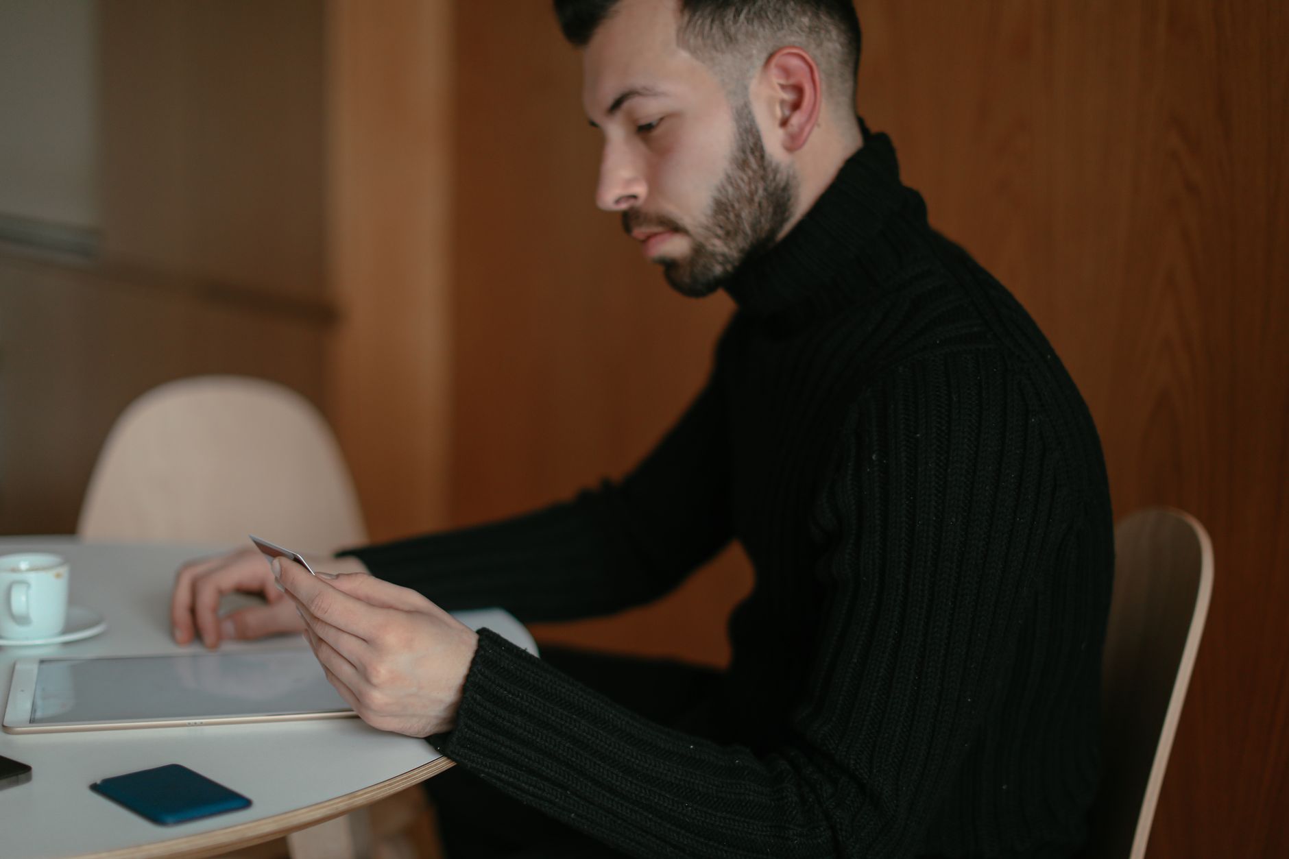 a person reviewing a credit report on a tablet at a kitchen table with a cup of coffee