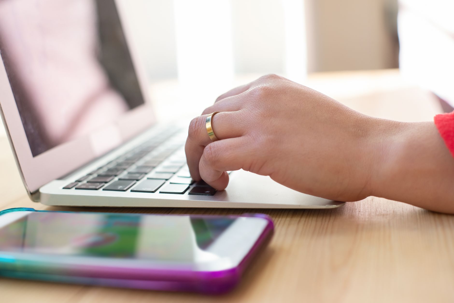 person changing email password on a laptop with a smartphone on the desk