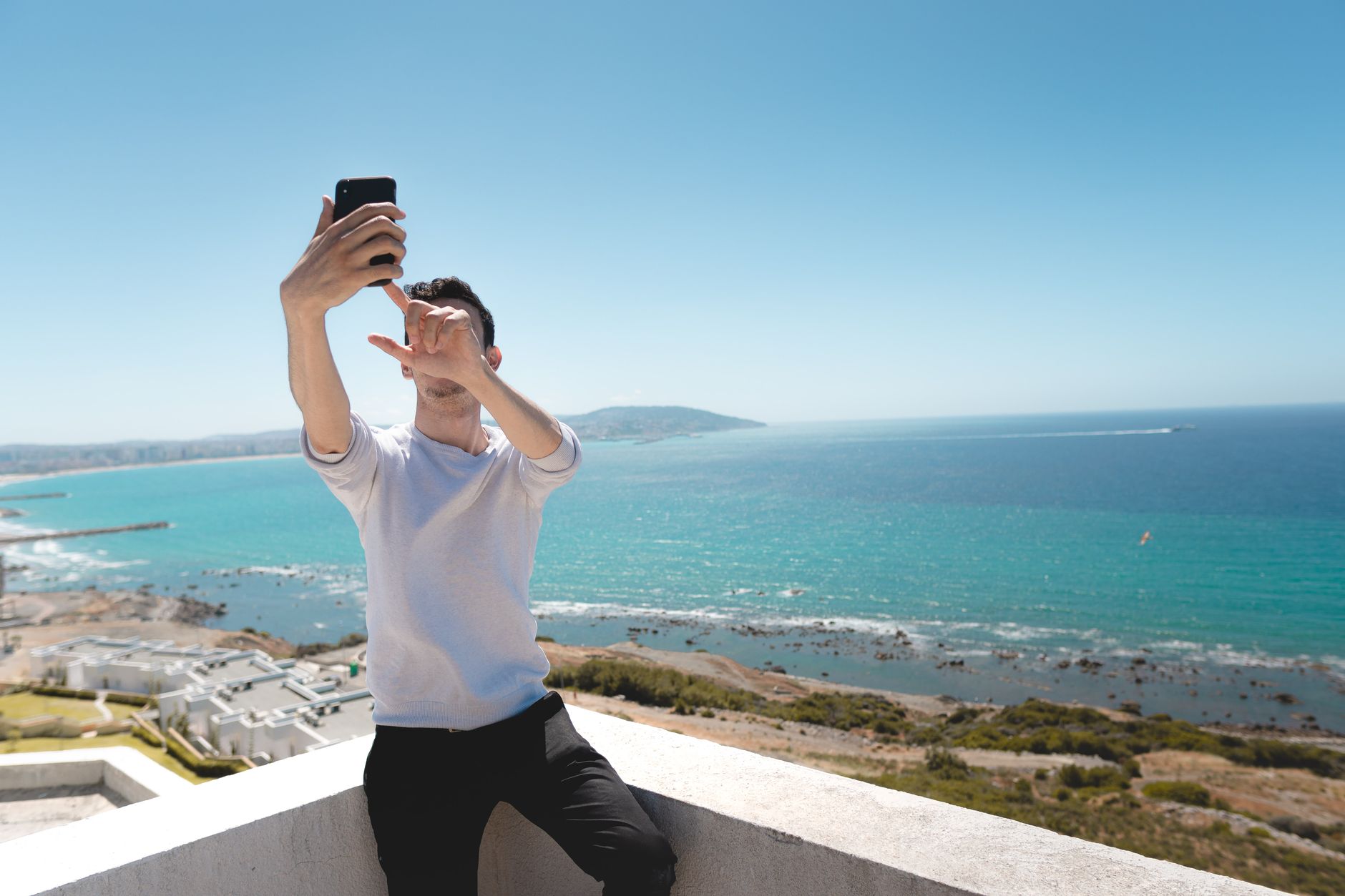 Man taking a selfie with a smartphone in soft natural light, showing how scammers may steal candid photos.