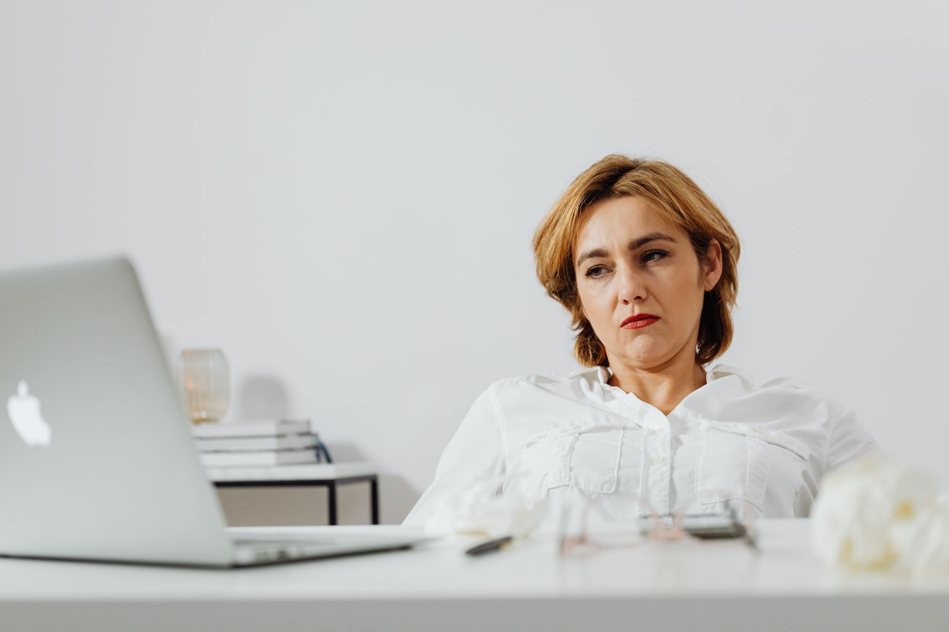 Woman looking at a laptop screen with a concerned expression while holding a credit card, illustrating a scam victim gathering evidence.