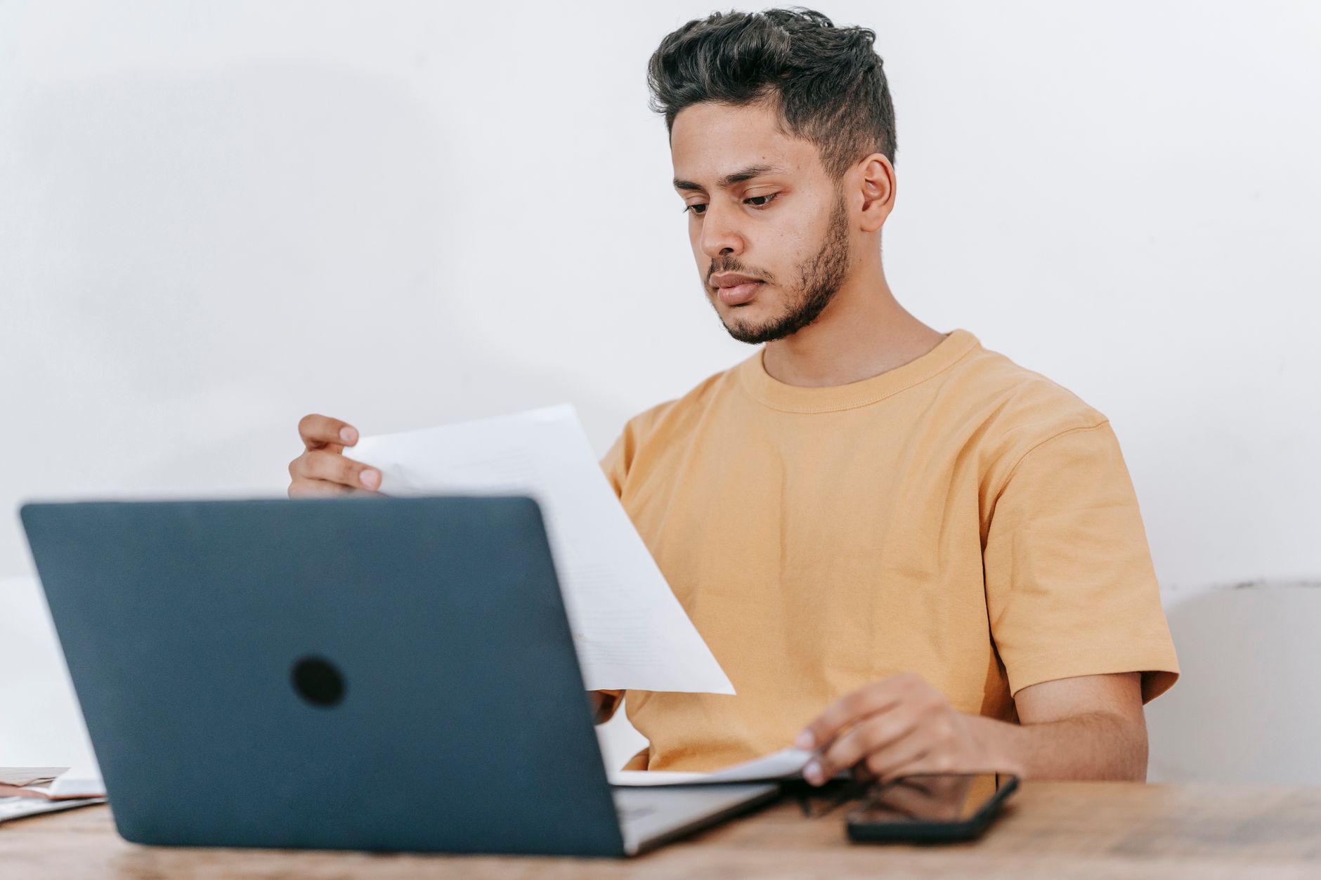 Person at a desk using a laptop to file an online fraud report, with a notepad and phone nearby.