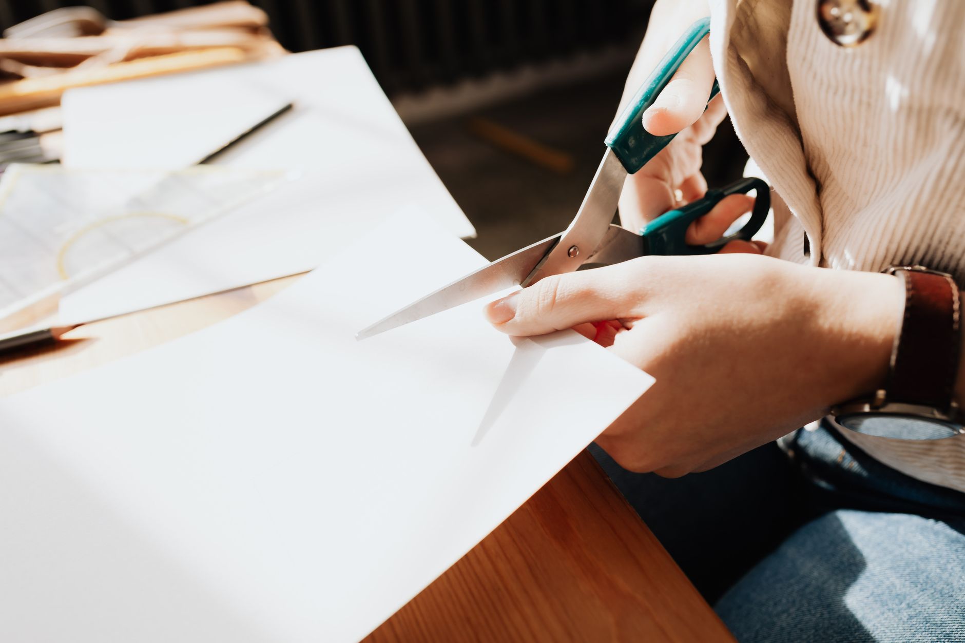 a person cutting a credit card with scissors at a kitchen table