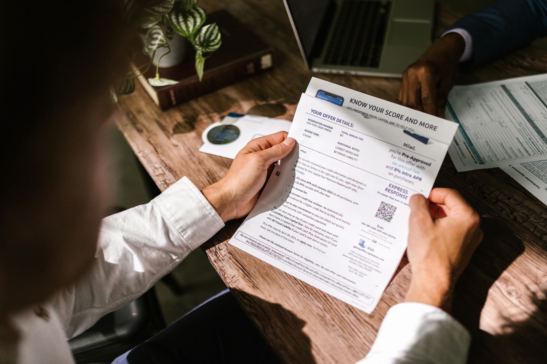 a person reviewing a printed credit report with a pen and laptop at home